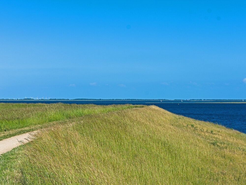 Pad over een grasdijk langs het blauwe water van het Grevelingenmeer bij Ouddorp